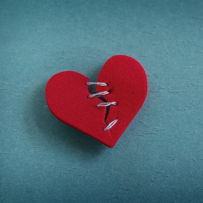 A red heart broken with threaded stitches